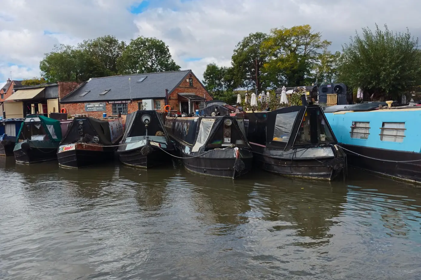 A row of narrowboats moored along a canal