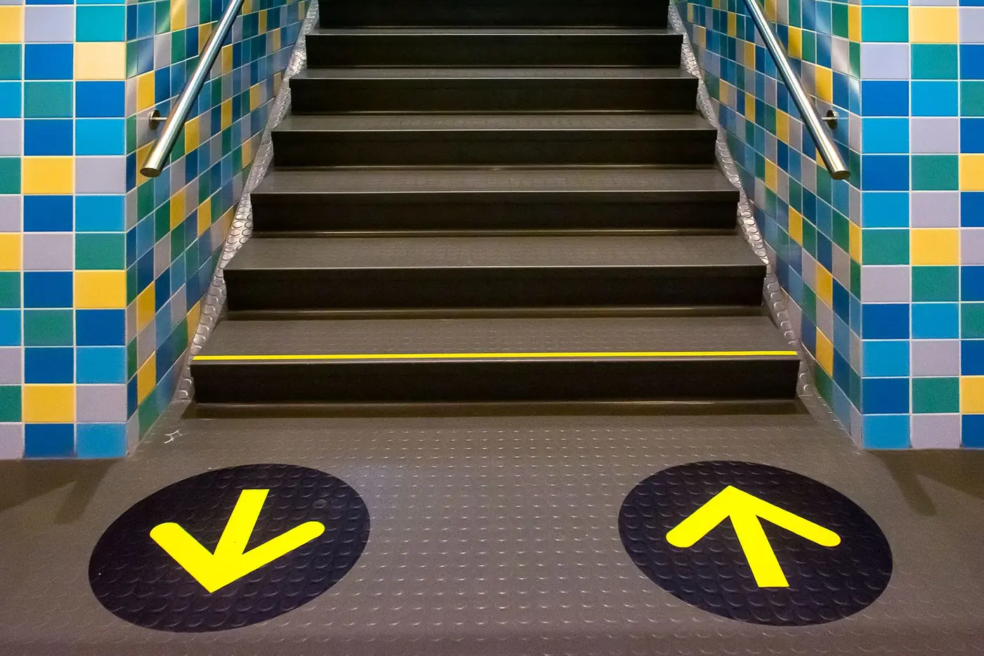 Yellow arrow floor graphics at the foot of a staircase