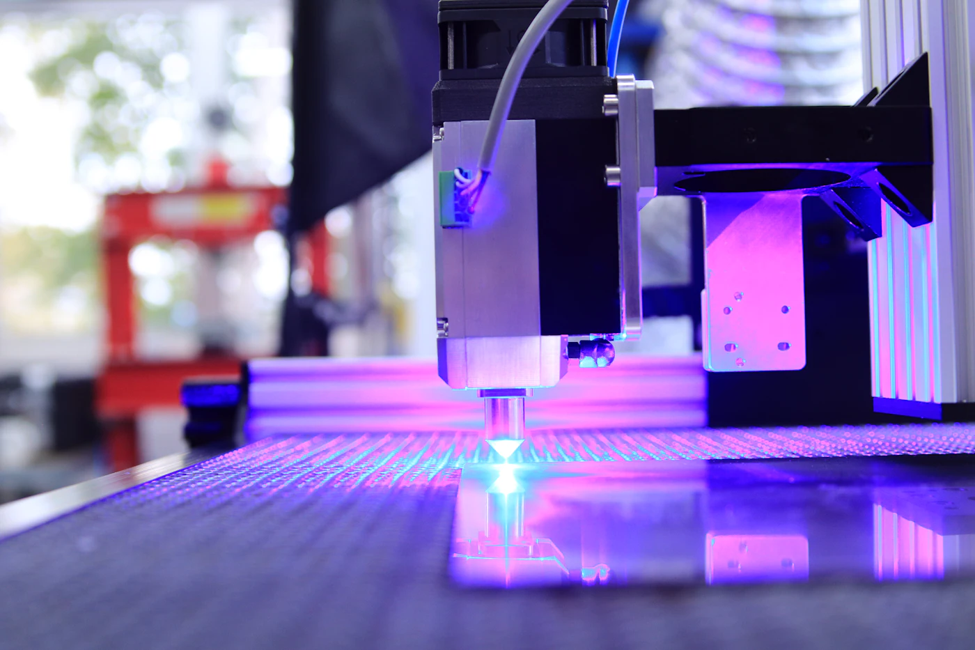 Laser cutting head firing a bright blue beam onto material on the machine bed