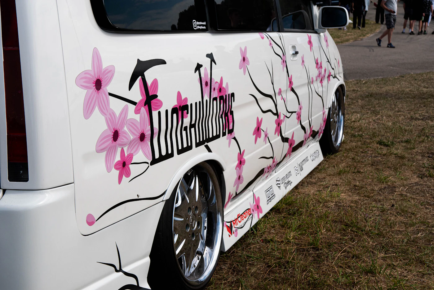 White van decorated with a cherry blossom vinyl wrap design and custom graphics