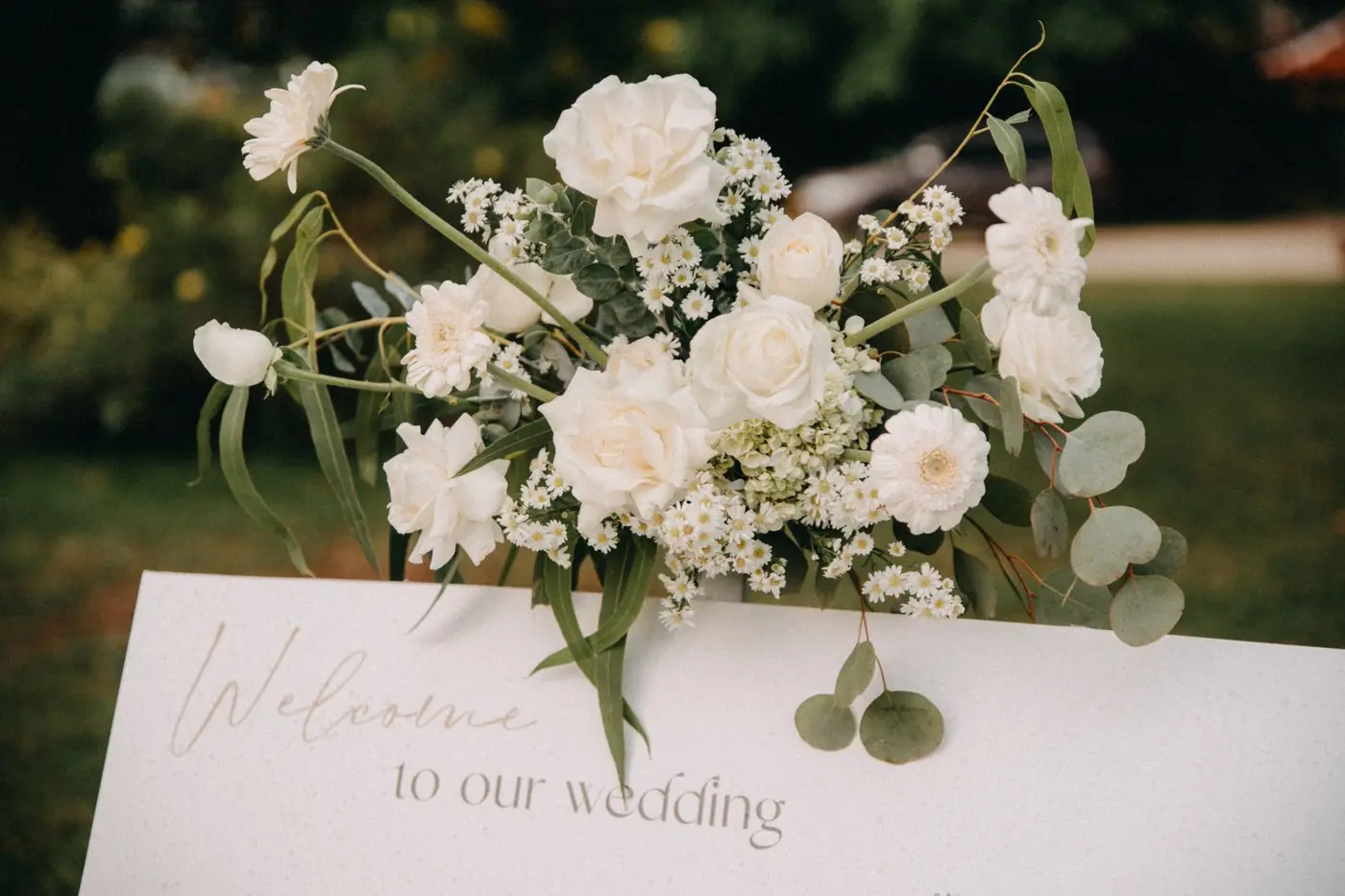 Welcome to our wedding sign with a white rose and eucalyptus arrangement