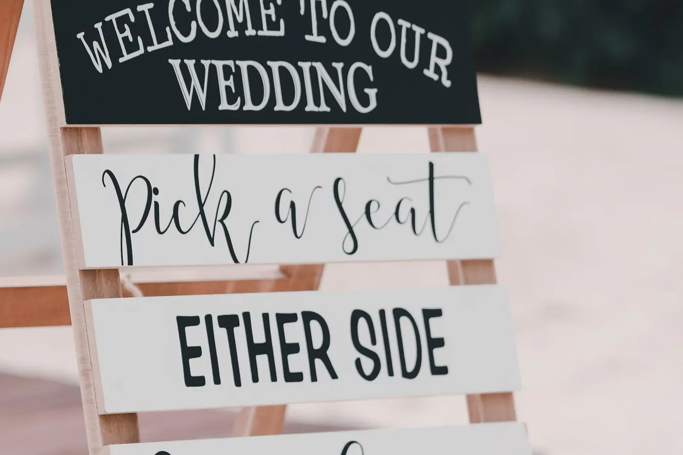 Wooden wedding sign with stacked boards reading pick a seat, either side